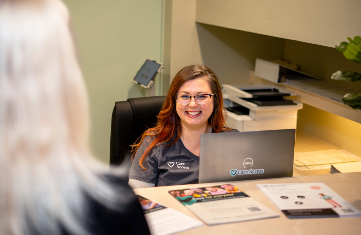 woman at desk smiling at person approaching